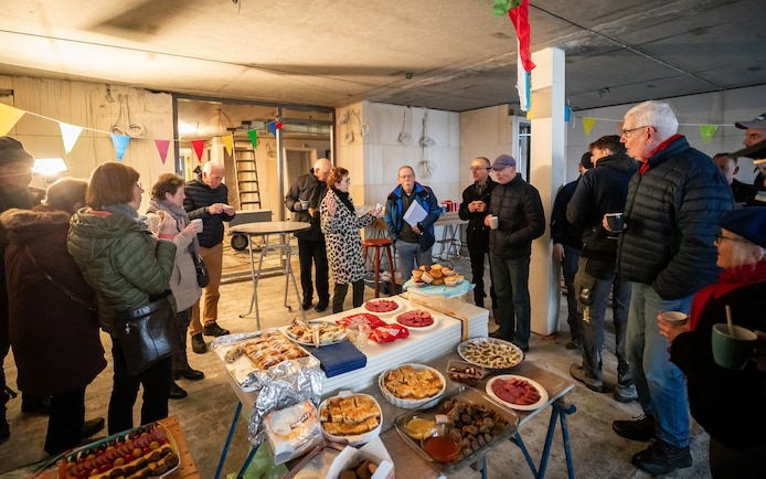 In hun toekomstige gemeenschappelijke ruimte vieren de aanstaande bewoners van De Mijlpaal in Nuenen woensdag het bereiken van het hoogste punt. In het midden met witte envelop in de hand staat voorzitter Jan Kempers.
