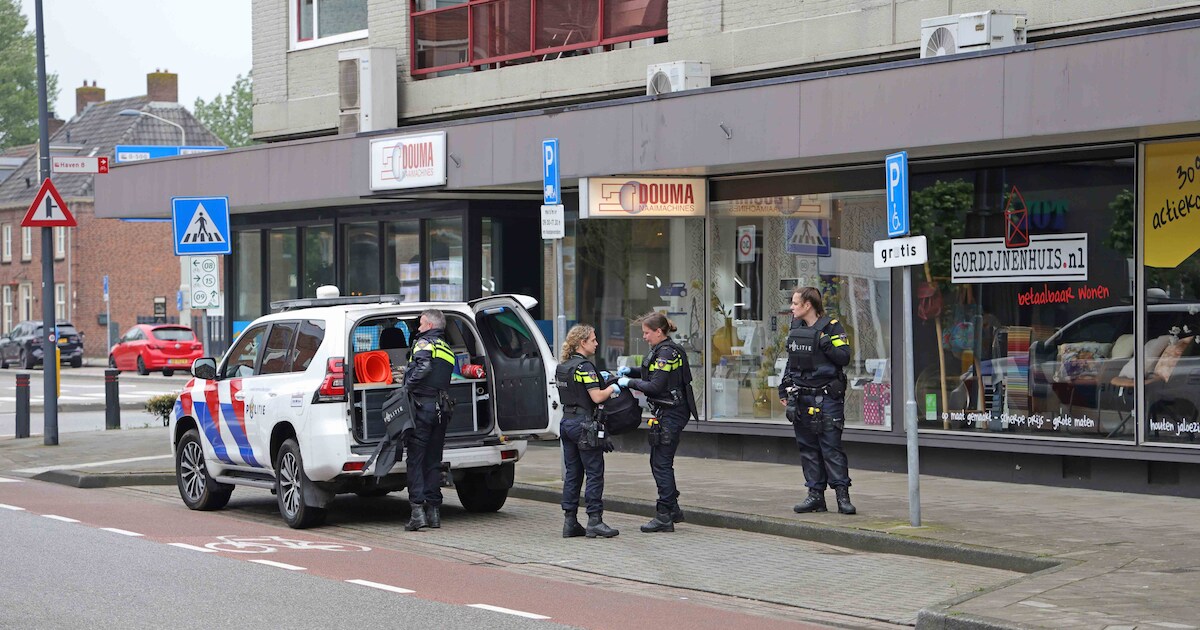 Agenten met kogelvesten houden man aan in naaiwinkel, personeel drukte ...