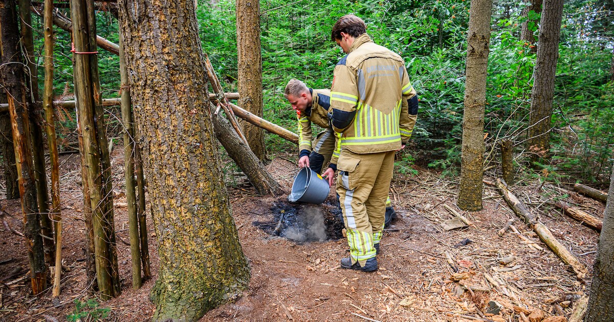 Brandweer blust smeulende resten van een kampvuur in bos bij Prinsenbeek | Foto