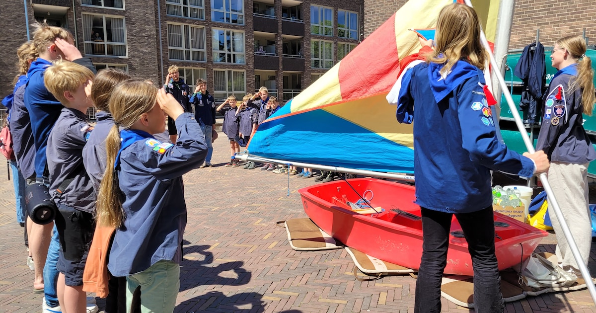 Waterscouting gaat over land naar de kerk met een kleine zeilboot ...